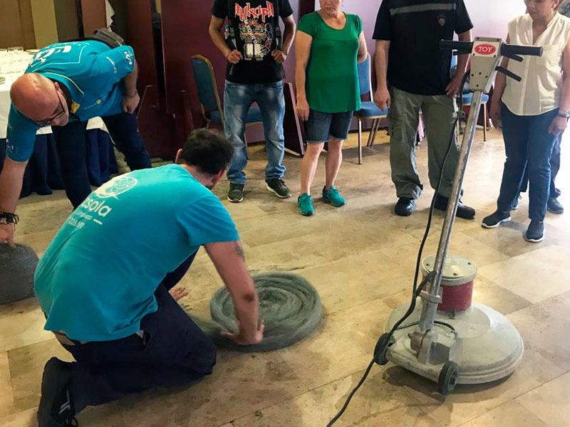 Profesionales de Luzsola haciendo una demostración práctica con materiales de limpieza a los alumnos en una formación en el interior